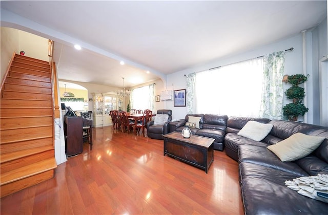 living area with arched walkways, stairway, and wood finished floors