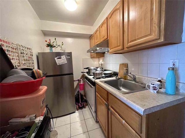 kitchen with electric stove, light countertops, freestanding refrigerator, a sink, and under cabinet range hood