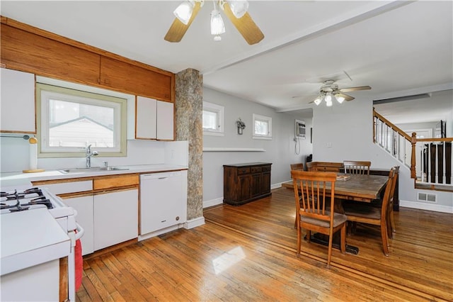 kitchen featuring visible vents, light wood-style flooring, white dishwasher, white cabinetry, and a sink