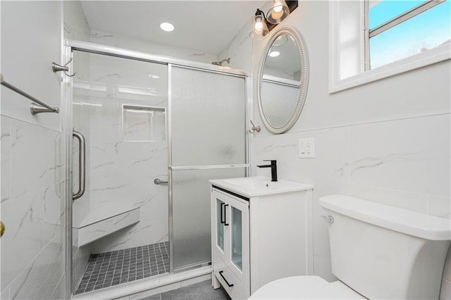 bathroom featuring a marble finish shower, toilet, tile walls, and vanity