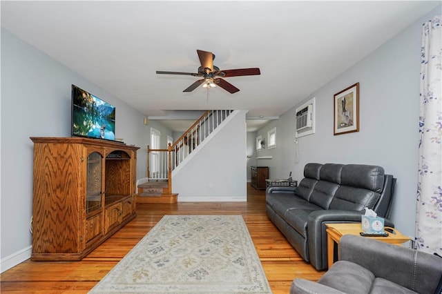 living room with ceiling fan, baseboards, stairway, a wall mounted air conditioner, and light wood-style floors