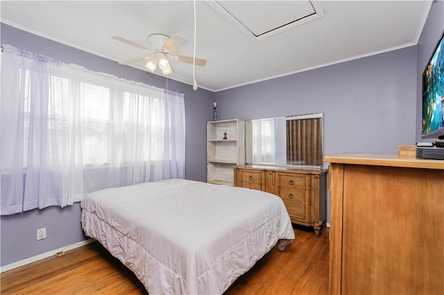 bedroom featuring a ceiling fan, crown molding, baseboards, and wood finished floors