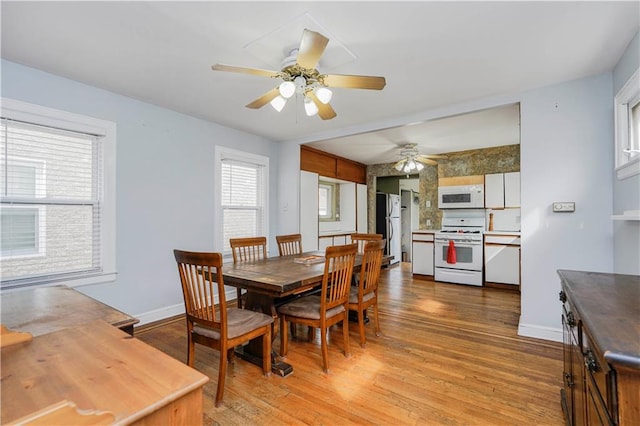 dining space with baseboards, ceiling fan, and light wood finished floors