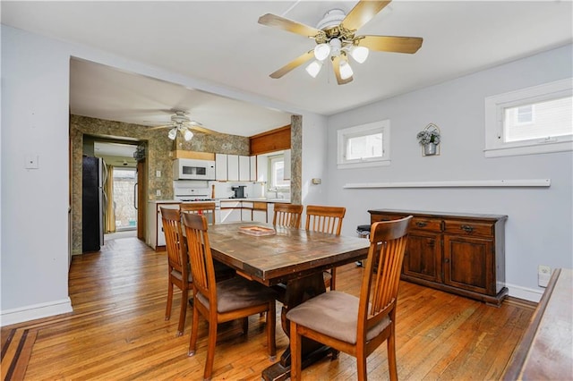 dining area featuring baseboards, a ceiling fan, and light wood finished floors