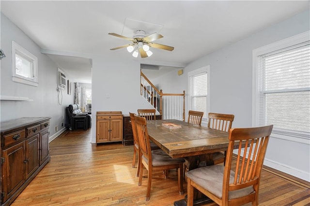 dining area with stairway, light wood-style flooring, a ceiling fan, and baseboards