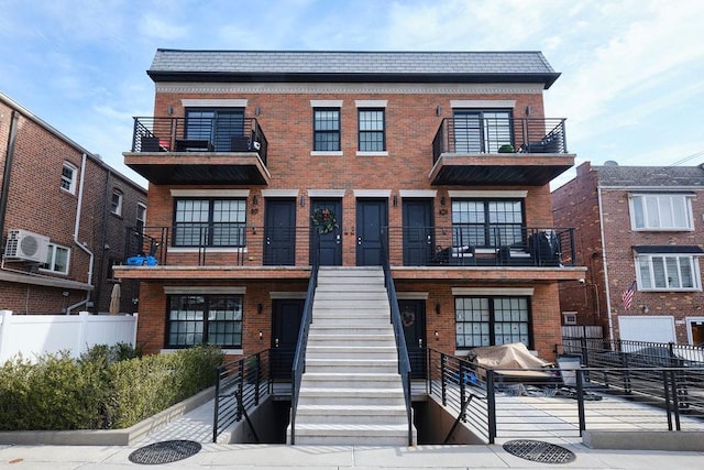 townhome / multi-family property featuring stairs, fence, and brick siding