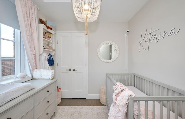 97 Battery Ave Unit 3B, Brooklyn, NY 11209 - bedroom featuring a chandelier, a closet, wood finished floors, a nursery area, and baseboards