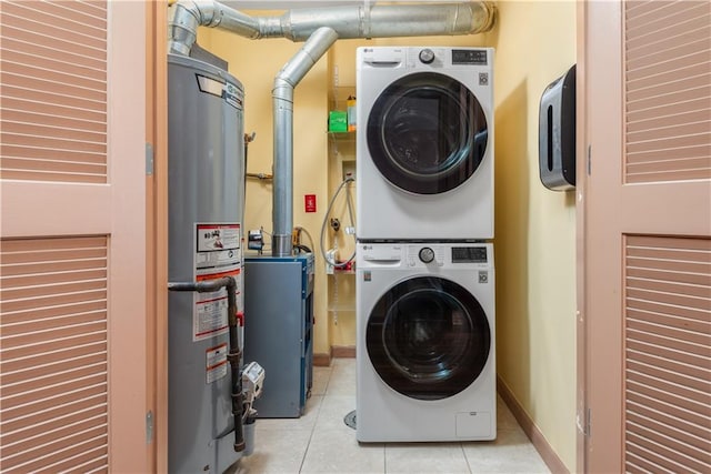 laundry room with water heater, tile patterned flooring, stacked washer / drying machine, baseboards, and laundry area