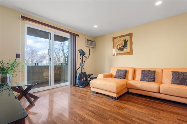 living area with recessed lighting, an AC wall unit, and wood finished floors