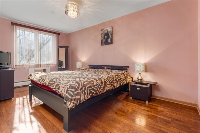 bedroom featuring baseboards, baseboard heating, and wood finished floors