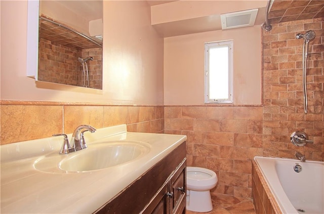 bathroom featuring toilet, vanity, tile walls, wainscoting, and washtub / shower combination