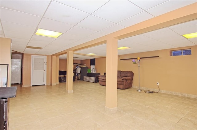 finished below grade area featuring baseboards, light tile patterned floors, and a drop ceiling