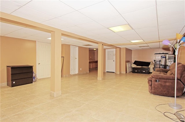 finished below grade area with a paneled ceiling and light tile patterned flooring