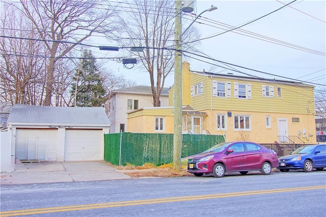 view of front of property featuring a garage, an outbuilding, and fence