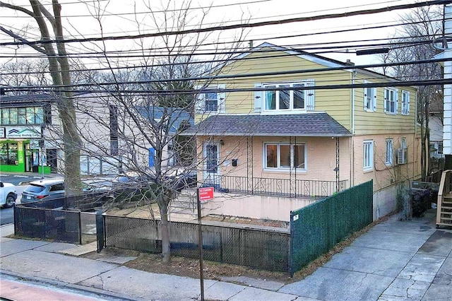 view of front of property with brick siding, a shingled roof, and a fenced front yard