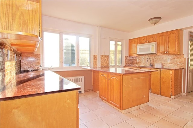 kitchen featuring a wealth of natural light, radiator heating unit, tasteful backsplash, and white microwave