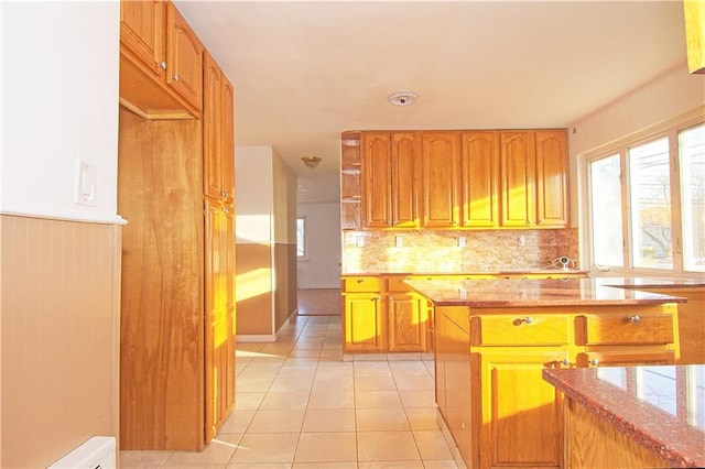 kitchen with light stone counters, decorative backsplash, brown cabinetry, and light tile patterned flooring