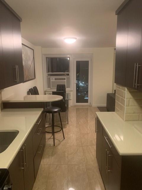 kitchen featuring electric stove, light countertops, decorative backsplash, dark brown cabinetry, and a sink