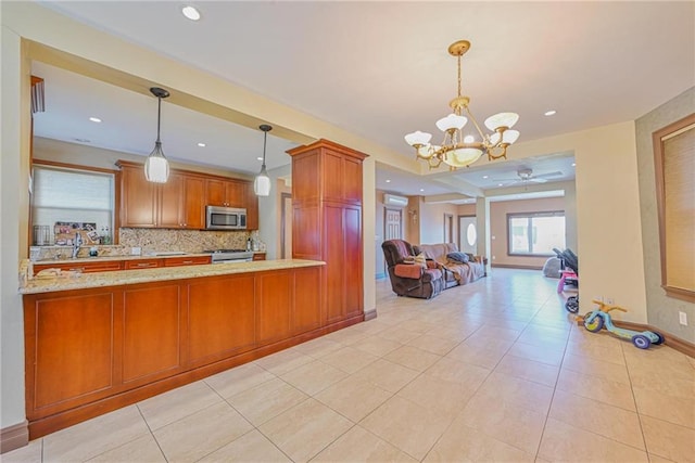 kitchen featuring stainless steel microwave, a chandelier, a ceiling fan, backsplash, and brown cabinetry