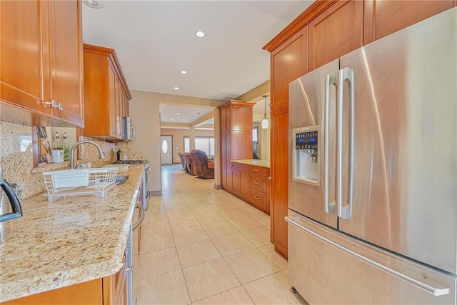 kitchen with stainless steel appliances, brown cabinets, backsplash, light tile patterned floors, and recessed lighting