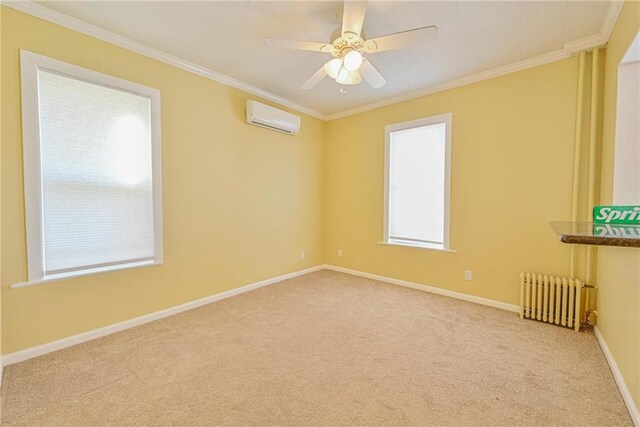 spare room featuring radiator, a wall mounted air conditioner, carpet flooring, ornamental molding, and baseboards