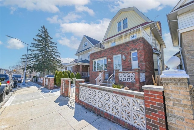 view of front of home featuring a fenced front yard, a gambrel roof, and brick siding