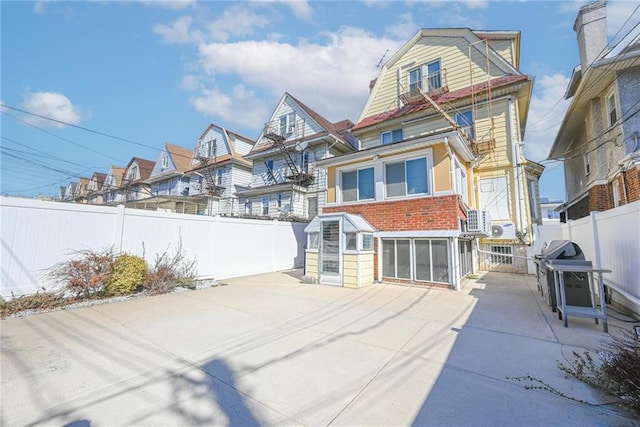 rear view of house featuring a fenced backyard, a residential view, a gambrel roof, and a patio