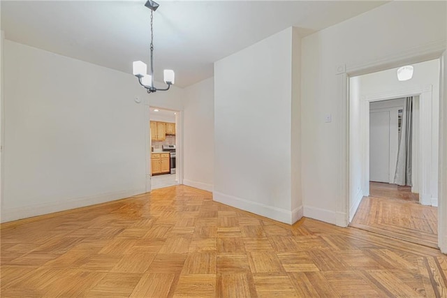 unfurnished room featuring baseboards and an inviting chandelier