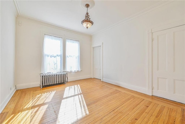 spare room featuring radiator heating unit, wood finished floors, and crown molding