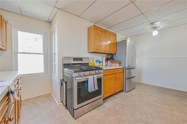 kitchen featuring a drop ceiling, appliances with stainless steel finishes, brown cabinetry, and light countertops