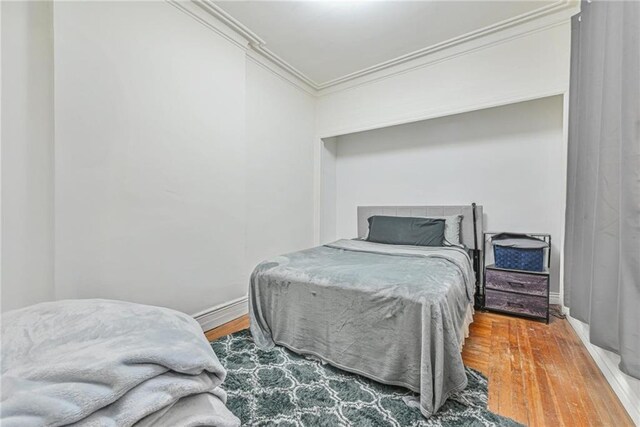 bedroom with wood finished floors and crown molding