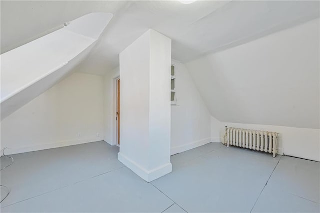 additional living space with baseboards, vaulted ceiling, and radiator