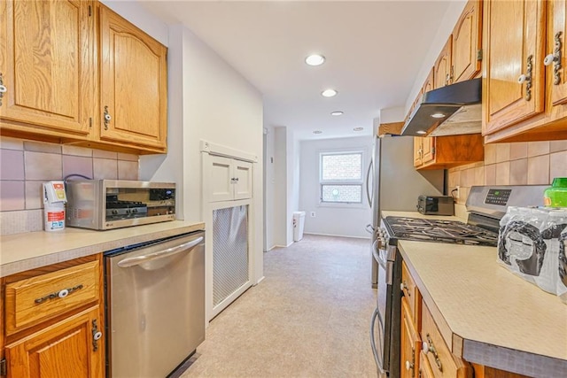kitchen featuring appliances with stainless steel finishes, light colored carpet, light countertops, under cabinet range hood, and recessed lighting