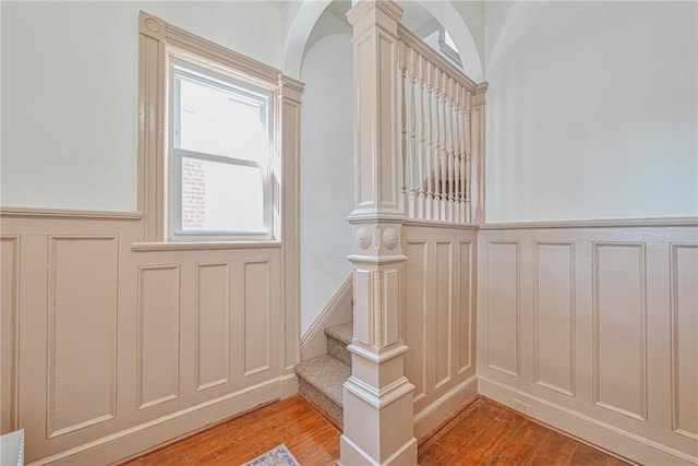 interior space featuring wood finished floors, a decorative wall, a wainscoted wall, and arched walkways