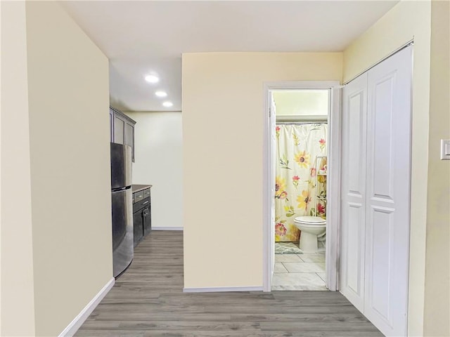 hall with recessed lighting, light wood-type flooring, and baseboards