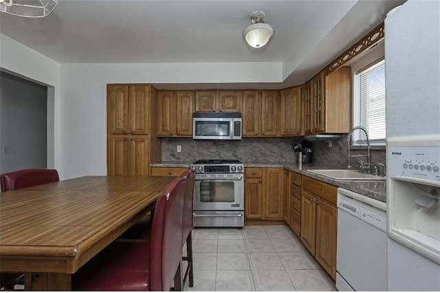 kitchen featuring a sink, light tile patterned floors, brown cabinetry, and stainless steel appliances