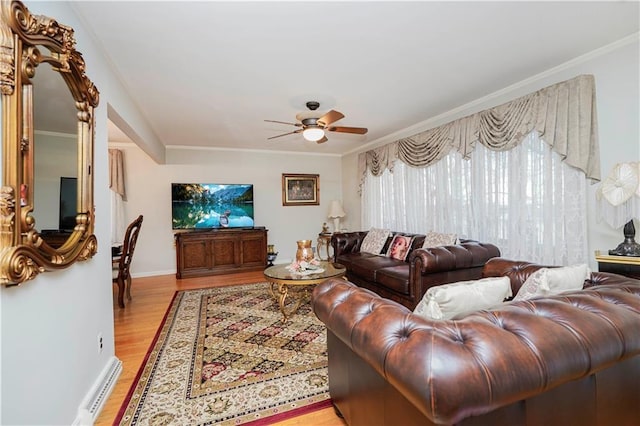 living area with crown molding, light wood-style flooring, baseboards, and ceiling fan