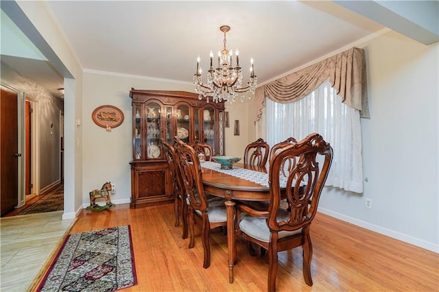 dining area featuring a notable chandelier, ornamental molding, baseboards, and light wood-style floors