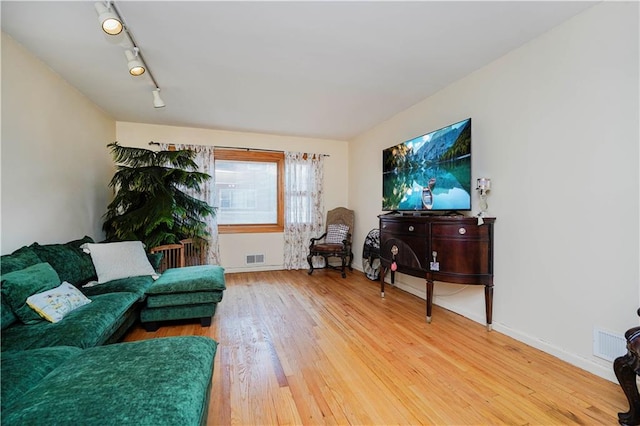 living room featuring track lighting, baseboards, visible vents, and light wood finished floors