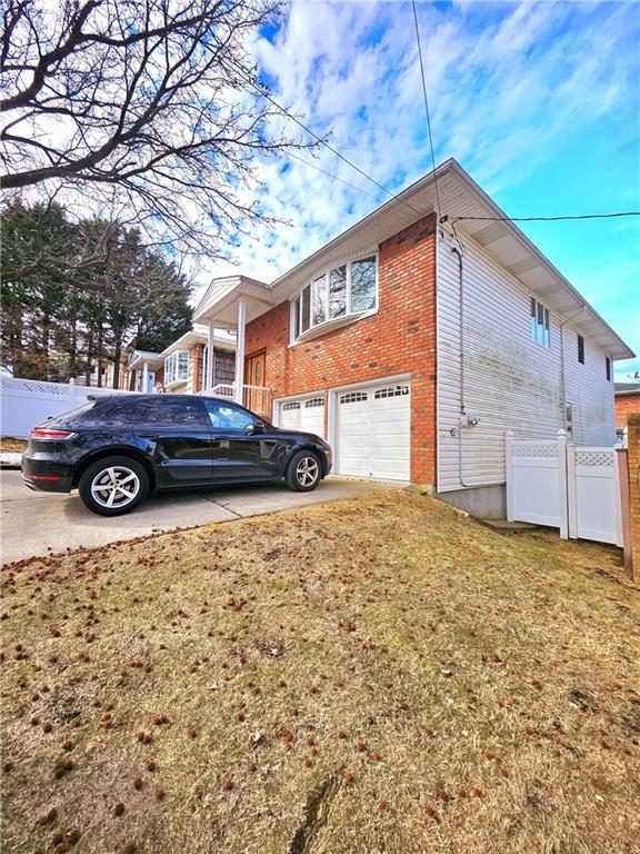 view of home's exterior with an attached garage, a yard, fence, and brick siding