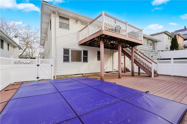 back of property with a gate, fence, a wooden deck, and stairs