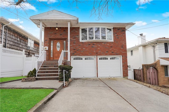 view of front of house with a garage, concrete driveway, a gate, fence, and brick siding