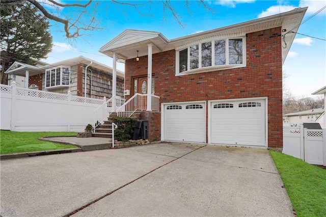 view of front of property featuring driveway, brick siding, an attached garage, and fence