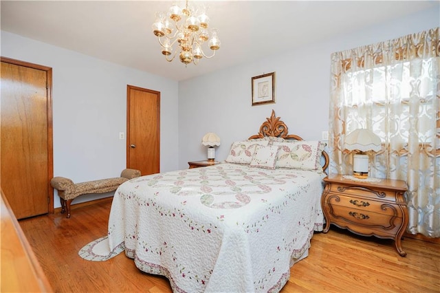 bedroom with light wood-style flooring and an inviting chandelier