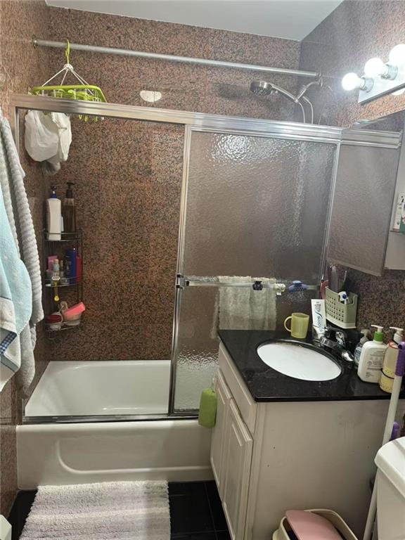 bathroom with tile patterned floors, vanity, toilet, and bath / shower combo with glass door