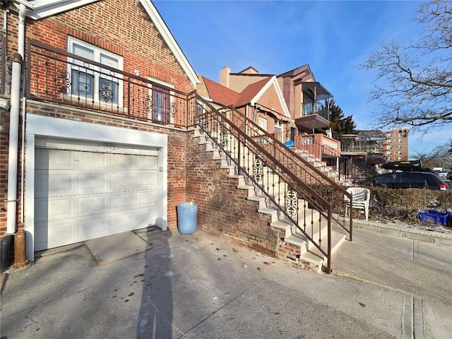 view of front of property with aphalt driveway, brick siding, stairway, and a garage