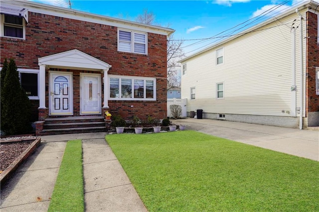 view of front of house featuring a front lawn, fence, and brick siding