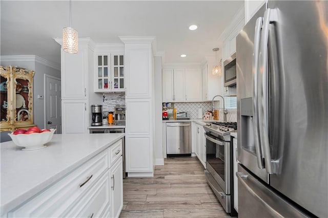 kitchen featuring light countertops, ornamental molding, light wood-style flooring, stainless steel appliances, and white cabinetry