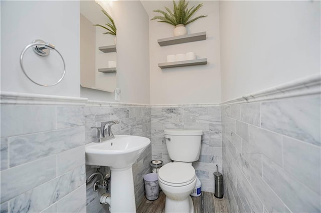 bathroom with wood finished floors, wainscoting, toilet, and a sink