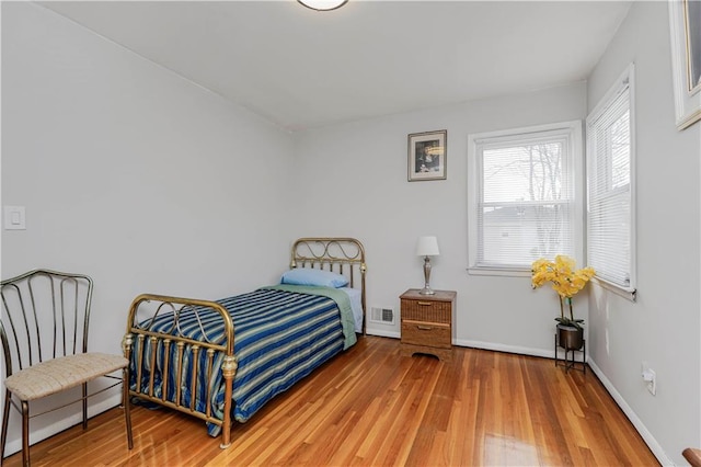 bedroom with wood finished floors, visible vents, and baseboards